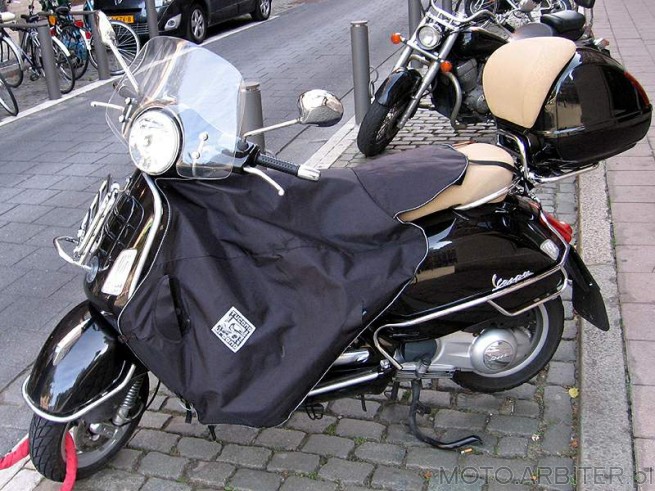 Vespa czarna z szybką, bagażnikiem z przodu,  kufrem z oparciem i motokocem